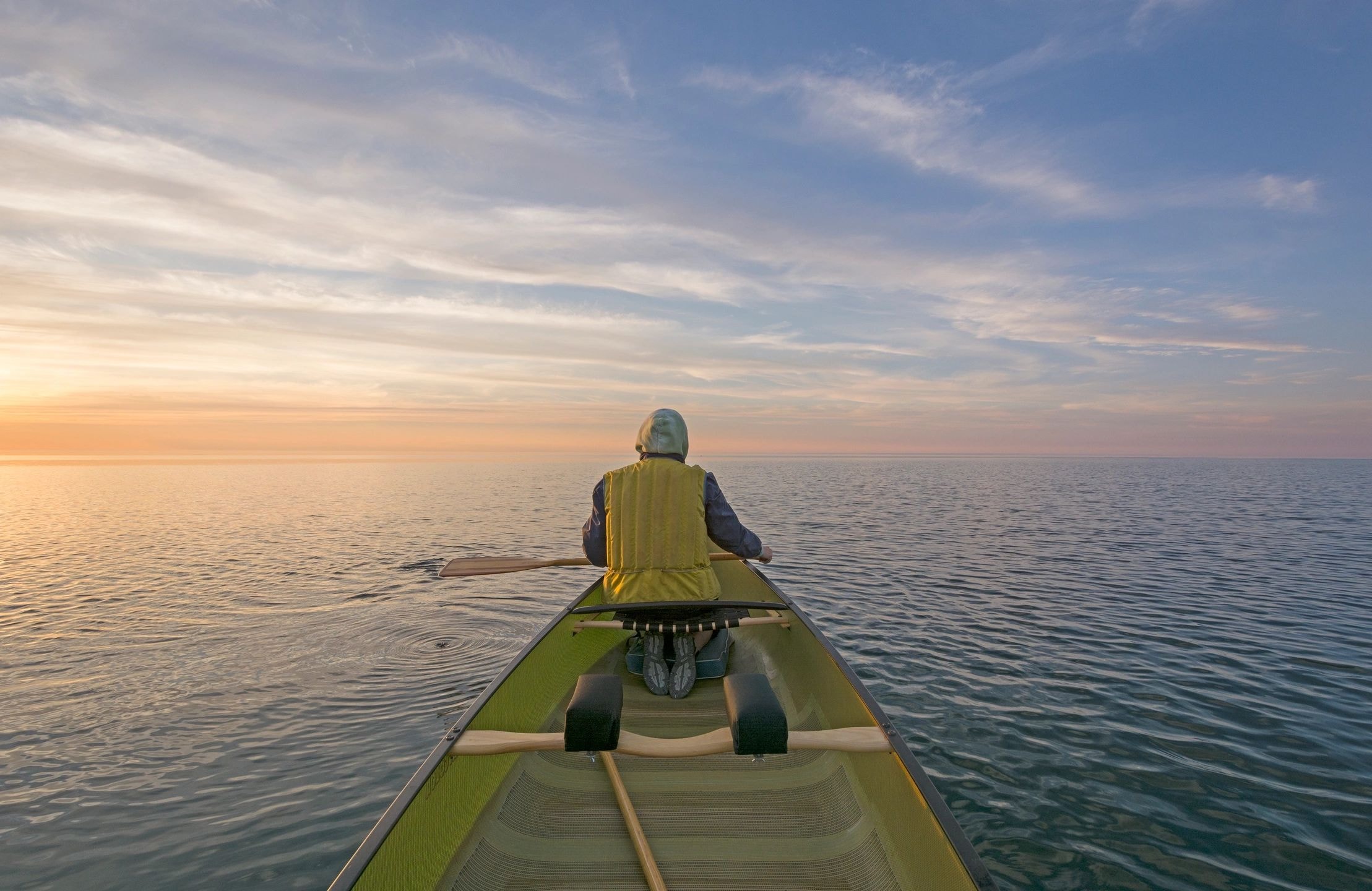Person kayaking on calm water at golden hour